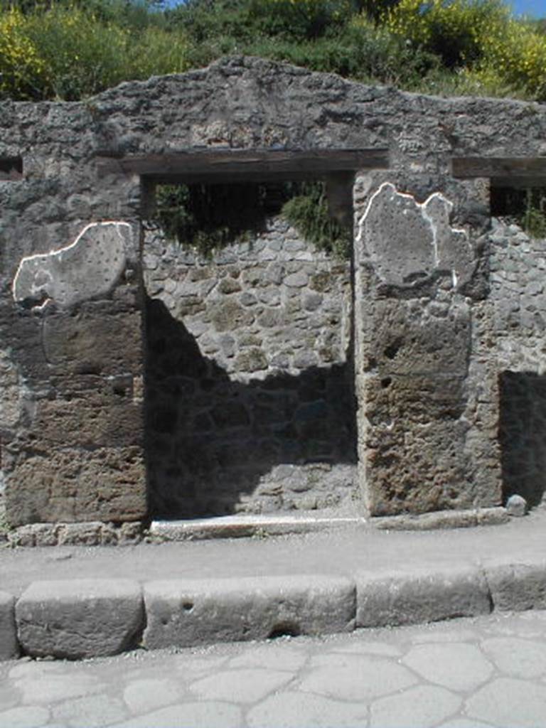 III.1.3 Pompeii. May 2005. Entrance doorway, partly excavated
According to Della Corte, on the pilaster to the left, between III.1.2 and 3, was written -
Cn(aeum) Hel[vium] Sabin(um)
aed(ilem) Pacuvius cu[pi]dus rog(at)     [CIL IV 7595]
See Della Corte, M., 1965.  Case ed Abitanti di Pompei. Napoli: Fausto Fiorentino. (p.342)
According to Cooley, this translates as –
Pacuvius eagerly asks for Cn. Helvius as aedile.
See Cooley, A. and M.G.L., 2004. Pompeii : A Sourcebook. London : Routledge. (p.121, F38)
Della Corte also said that on the right pilaster, above an old plaster but brought to light by the fall of the most recent plaster, was painted a large red anchor.  He thought this may have alluded to the activity of the proprietor, perhaps in maritime commerce. Today, the anchor is no longer visible.
