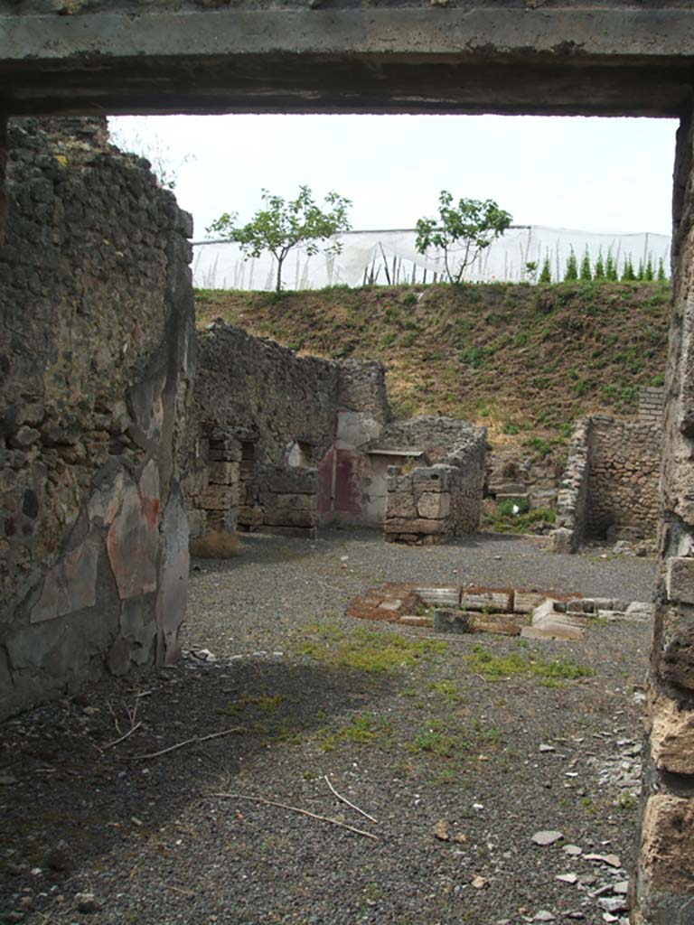 V.2.g Pompeii. May 2005. Looking north through room ‘m’ the tablinum, across atrium to entrance. 
According to NdS, the tablinum was on the south side of the atrium between the cubiculum ‘h’ on the left, and the corridor ‘L’ on the right.
The tablinum had a window in its south wall which led onto the north portico of the garden.
It had opus signinum flooring, and walls decorated with red panels except for the central ones which were yellow.
In the middle of all of the panels were small rectangular squares with the usual circular crudely painted landscapes.
At the foot of the east wall was a recess for a bed, and a travertine one-legged support was found there.
Found on the red plaster of the dado of the west door-jamb, on the side pointing towards the entrance, (on the left of this photo), was the graffito:
CAESARIS
See Notizie degli Scavi di Antichità, 1896, (p.420-21).
