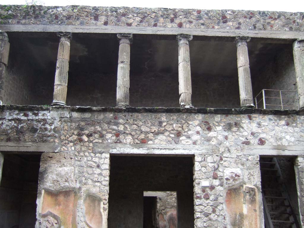 V.2.h Pompeii. December 2005. Upper floor cenaculum with columns, looking south across atrium.
According to NdS, in the atrium several parts of tufa fluted columns were found. 
They were of various sizes, with bases and Ionic capitals.
According to Sogliano, Mau believed that the said Ionic columns belonged to a portico above the rooms ‘e’, ‘f’ and ‘g’, which would have been open onto the rear side of the atrium.
In 1896 Sogliano thought this was certainly possible, as was seen in other places in Pompeii, but he would not confirm this with certainty, considering above all the lack of robustness of the supporting walls.
See Notizie degli Scavi di Antichità, 1896, (p.422).
See Mau in Bullettino dell’Instituto di Corrispondenza Archeologica (DAIR), VIII, 1893, (p.16)
By 1903, Sogliano agreed with Mau, as he wrote that “it was noted that above the tablinum and the two adjacent rooms was a portico or loggia open onto the atrium”.
See Sogliano in Atti del Congresso Scienze e Storiche, 19/4/1903, (p.322)
