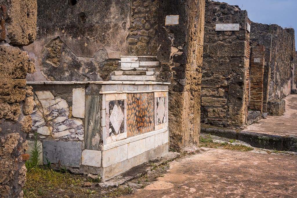 V.4.7, Pompeii. July 2024. Looking east along counter on north side of Via di Nola. Photo courtesy of Johannes Eber.