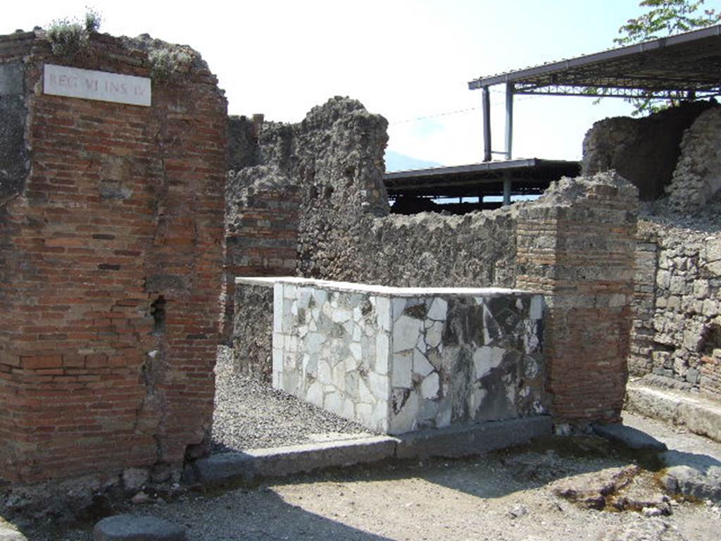 VI.4.1 Pompeii. May 2006. Entrance doorway with counter. 
According to Curti, in 1818, in the face of the Via Domiziana [todays Via Consolare], on the corner of a triangular insula, was found a taberna of a seplasarius [a trader in perfumes and unguents] or a pharmacist. For exhibition, he had painted a large snake that bites a pine cone. The serpent was the attribute of Hygeia, the goddess of health, and of Aesculapius: it is still the emblem of today's [1873] pharmacies. In Pompeii, as we have noted elsewhere, it was valid for other purposes, and therefore would not have been enough to fix the designation of this taberna as a pharmaceutical workshop, had it not been found inside various other medicines, chemical preparations, pots with dried medicines and pills, spatulas, and a bronze box with compartments containing drugs, and a porphyry blade to spread and smooth the poultices.
See Curti P. A., 1873. Pompei e le sue rovine: Part 2. Napoli e Milano, p. 268.
According to Della Corte, this thermopolium or workshop was always described in the old bibliographies as an “officina farmaceutica”
Why?  Many chemical preparations and many jars with dried medicines and pills were found here.
As medical substances, they are unknown, however as the results have never been analysed. 
The notion that it was an “officina farmaceutica”, however was, and stays, simply circumstantial.
See Della Corte, M., 1965.  Case ed Abitanti di Pompei. Napoli: Fausto Fiorentino. (p.42)
