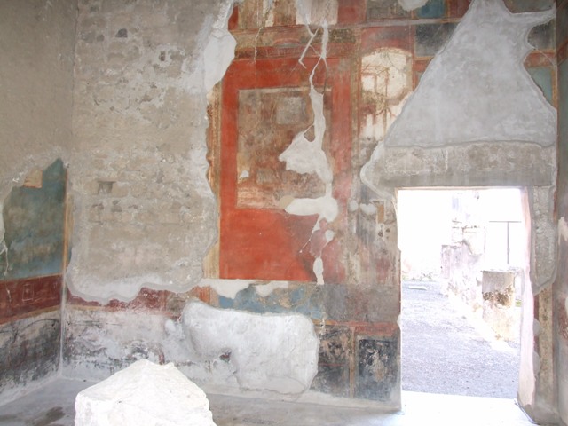 VI.9.6 Pompeii. March 2009. Room 8, painted decoration from upper centre of west wall.
Kuivalainen describes the central figure as -
“An enthroned frontal figure holding a cantharus in his right hand and a thyrsus in his left; the hips and legs are covered with a himation.”
He comments that –
“The identification of this partly robed and effeminate figure as Bacchus with his characteristic attributes is more likely than Libera or Ariadne, who are seldom depicted in this pose.”
See Kuivalainen, I., 2021. The Portrayal of Pompeian Bacchus. Commentationes Humanarum Litterarum 140. Helsinki: Finnish Society of Sciences and Letters, (p.100, B10).
