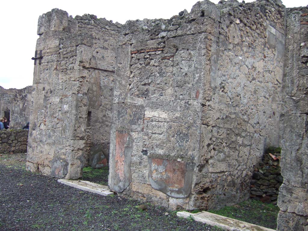 VI.13.6 Pompeii. December 2005. Rooms on east side of the atrium. 
The doorway to a cubiculum is on the left, this would be the one where paintings were found on the walls but left in situ, and now lost.
According to Presuhn, “in a cubiculum on the right side of the atrium, was a wall painting also well preserved, showing Venus and Adonis, favoured subject of Pompeian painters (Helbig 331). Many paintings found in this house were taken to the Naples Museum, but others were left, and are now destroyed”.
See Presuhn, E. Pompei les dernières fouilles de 1874-75.

According to PPM –
«In the north wall in the north-west corner is a doorway into the east ala : the red zoccolo painted with panels with plants was edged from the yellow middle zone by a carpet-border with triangles by a white band. The upper cornice of moulded stucco was blue, with a white upper area.
There was no shortage of figurative subjects completely lost and documented only by Fiorelli's brief descriptions (Fiorelli, Descrizioni, p.424) – a Satyr with a Bacchante, Leda with the swan, Adonis sitting on the lap of Venus, accompanied by three cupids.”
See Carratelli, G. P., 1990-2003. Pompei: Pitture e Mosaici. V (5). Roma: Istituto della enciclopedia italiana, (p.165).

