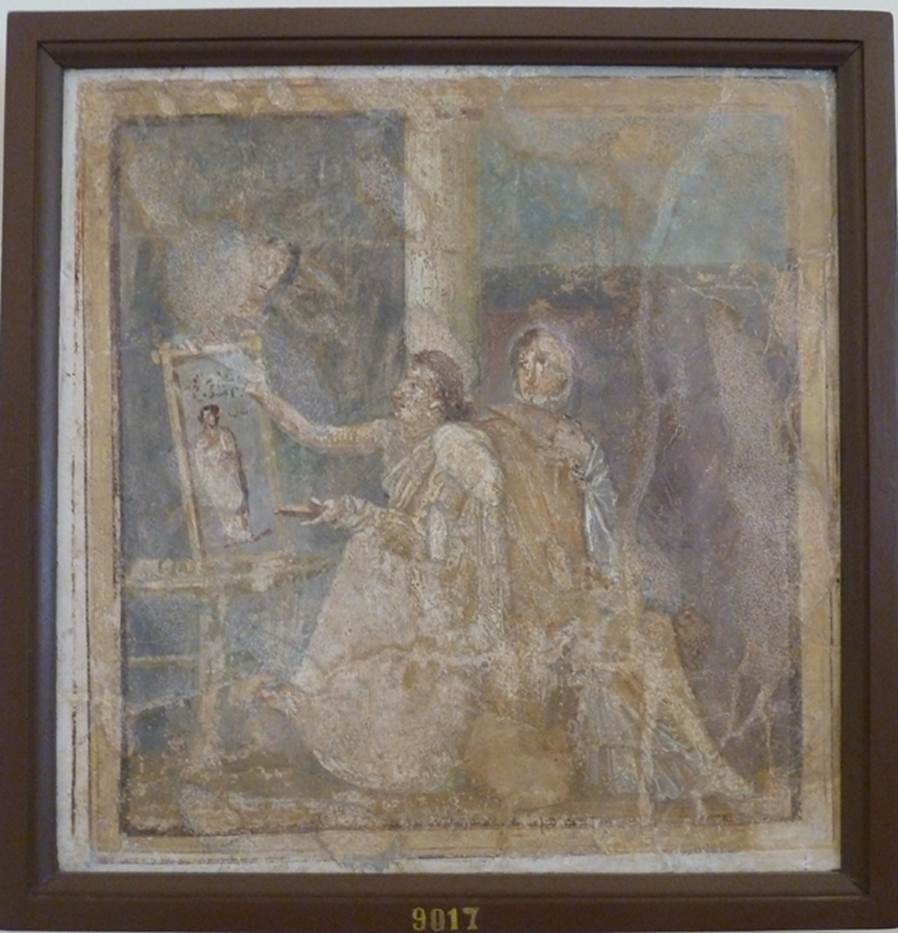 VI.14.42 Pompeii.  Found in Cubiculum (3), the room on the south (or right) of the entrance corridor.   Wall painting of woman painting.  
She holds a palette in her left hand and is painting a picture on a table or easel with the right.  A woman in yellow, with a white mantel over her shoulder, sits next to her. The woman admires the painting which is of a woman in a yellow robe. Now in Naples Archaeological Museum.  Inventory number 9017. See Helbig, W., 1868. Wandgemälde der vom Vesuv verschütteten Städte Campaniens. Leipzig: Breitkopf und Härtel. (1444). See Richardson, L., 2000. A Catalog of Identifiable Figure Painters of Ancient Pompeii, Herculaneum. Baltimore: John Hopkins. 
(p.120, he described it as a Genre scene with woman painting a picture, found in cubiculum 3, south of fauces).
