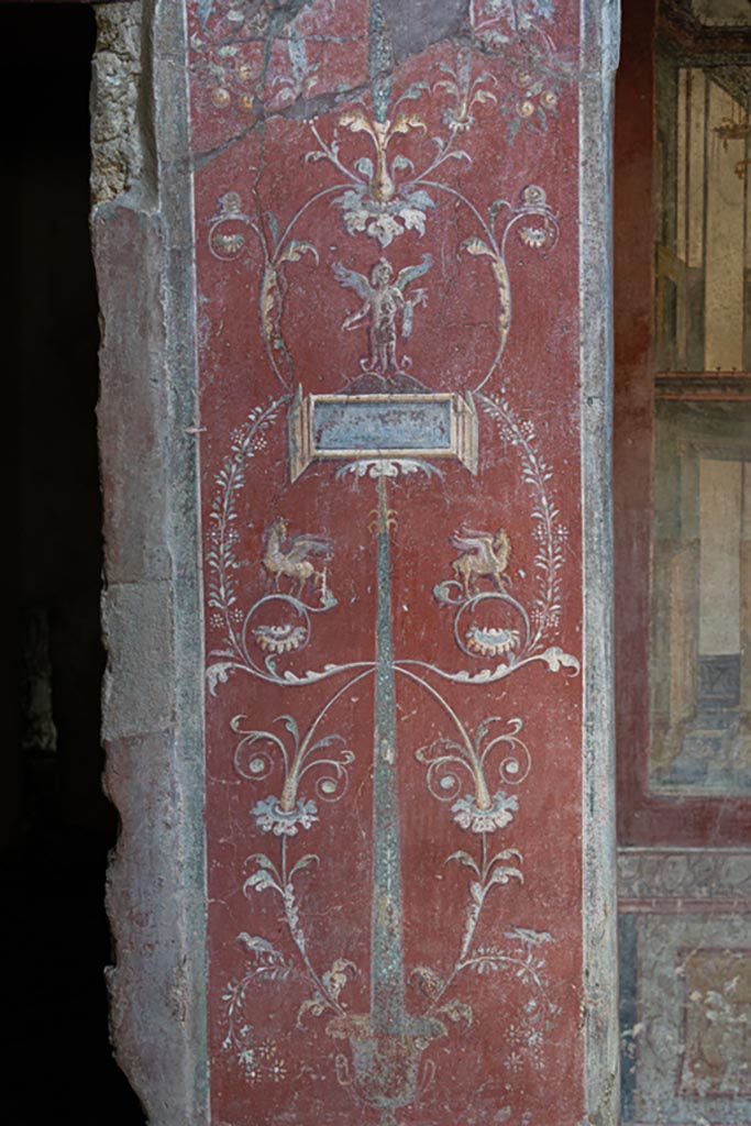 VI.16.15 Pompeii. September 2021. 
Atrium B, wall painting of face or mask between doorway to room E and room D at base of pilaster. Photo courtesy of Klaus Heese.
