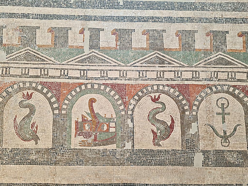 VI 17.10 Pompeii ?. June 2024.  
Detail from mosaic of “doors”, starting with one dolphin, and a stern of a ship with rudder, another dolphin and an anchor.  
On display in Naples Archaeological Museum, Room CXXXIV.  Photo courtesy of Giuseppe Ciaramella. 
