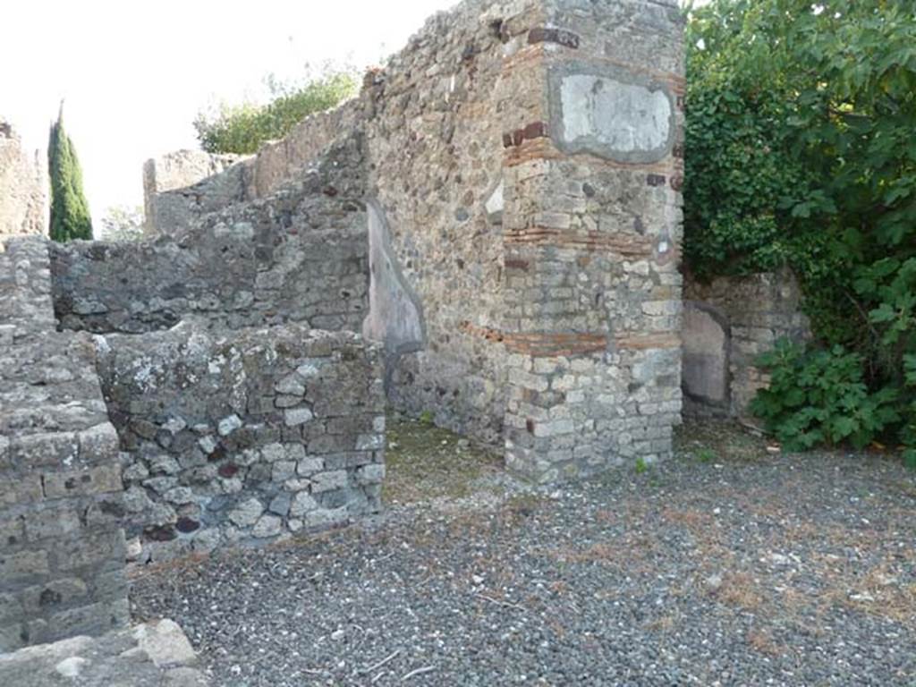 VI.17.10 Pompeii. September 2015. South side of atrium, with two of the three doorways to cubicula.  According to Allroggen-Bedel – 
The room described by La Vega, as No.10, corresponded to the preserved remains in the middle room left from atrium, doorway on right of photo. 
According to La Vega – 
“From the 9th to the 17th November we excavated this room, which had a floor of black mosaic with white border all around, and white rosettes sprinkled throughout, and it was found patched up by the ancients at a site close to the threshold. The plaster was painted with following format: Red zoccolo with a few lines, and large fronds of herbs, the panels above were yellow with vases/pots in the middle, the bands that one could distinguish were red, decorated with grotesque architecture: the decoration above had a white background with various bands and grotesque architecture. On one side of this room, there was in the wall, an undercut recess that ends with the floor. It was preserved without lifting a piece. (Si e conservato senza levarci alcun pezzo).”

