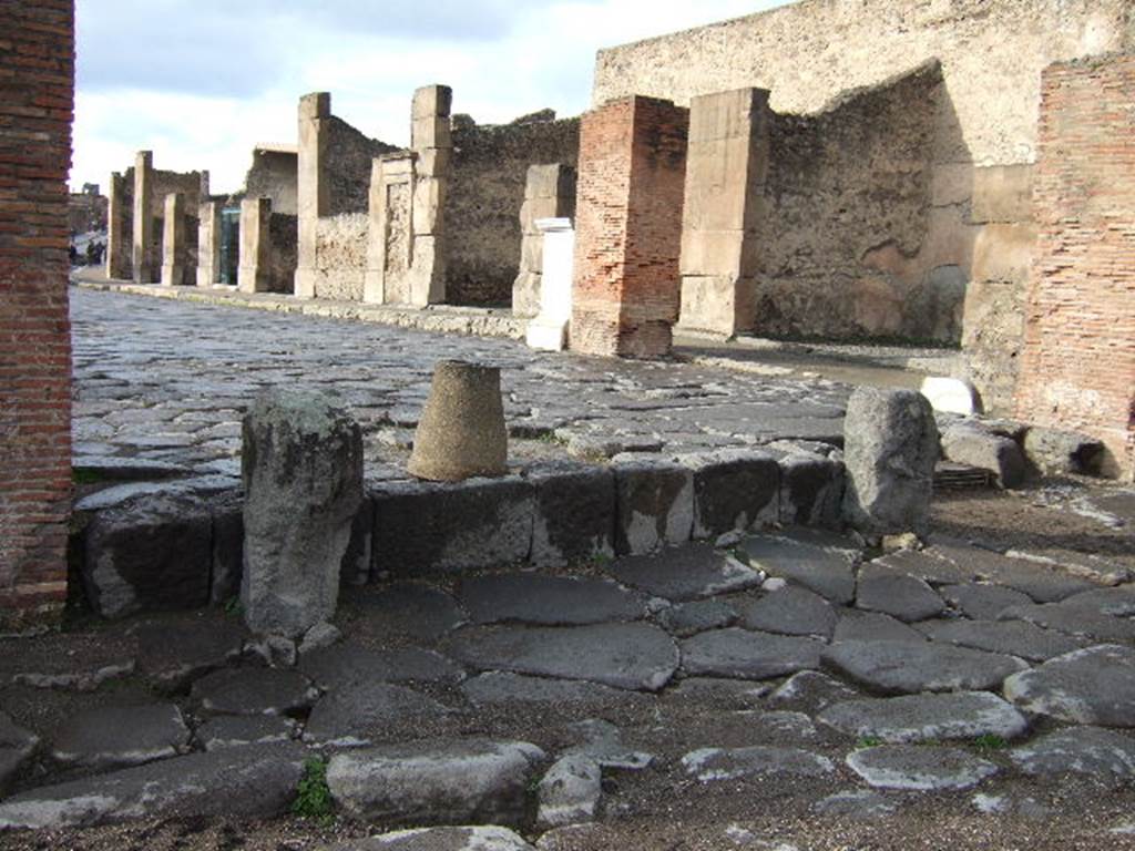 Looking west along Via dell Abbondanza, Pompeii.  VII.1.12 is first shop on right, near where the statue of Holconius Rufus was found (the white marble pedestal).

