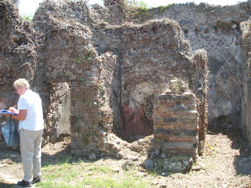 VII.3.8 Pompeii. May 2005. 
Looking south. Doorway to latrine “f”, small cubiculum “d” with red painted plaster and corridor to large rear room “e”.

