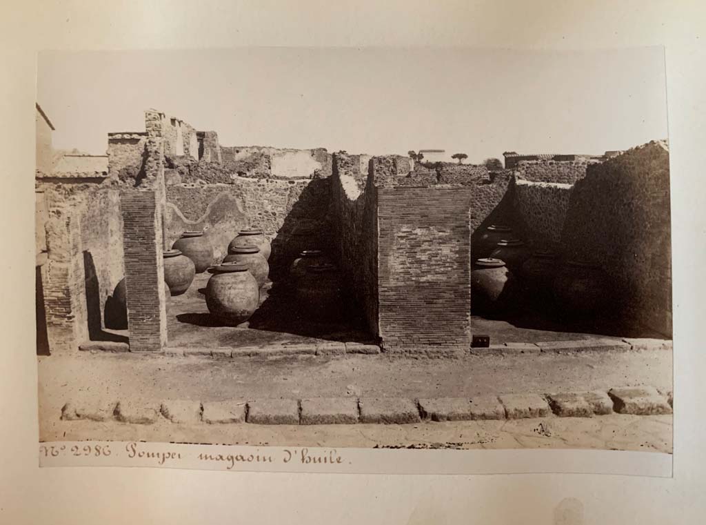 VII.4.13, in centre left, and 14, in centre right. 
Album by M. Amodio, c.1880, entitled “Pompei, destroyed on 23 November 79, discovered in 1748”.
According to the writing on this photo, this was a warehouse (storehouse) for oil. Photo courtesy of Rick Bauer.
