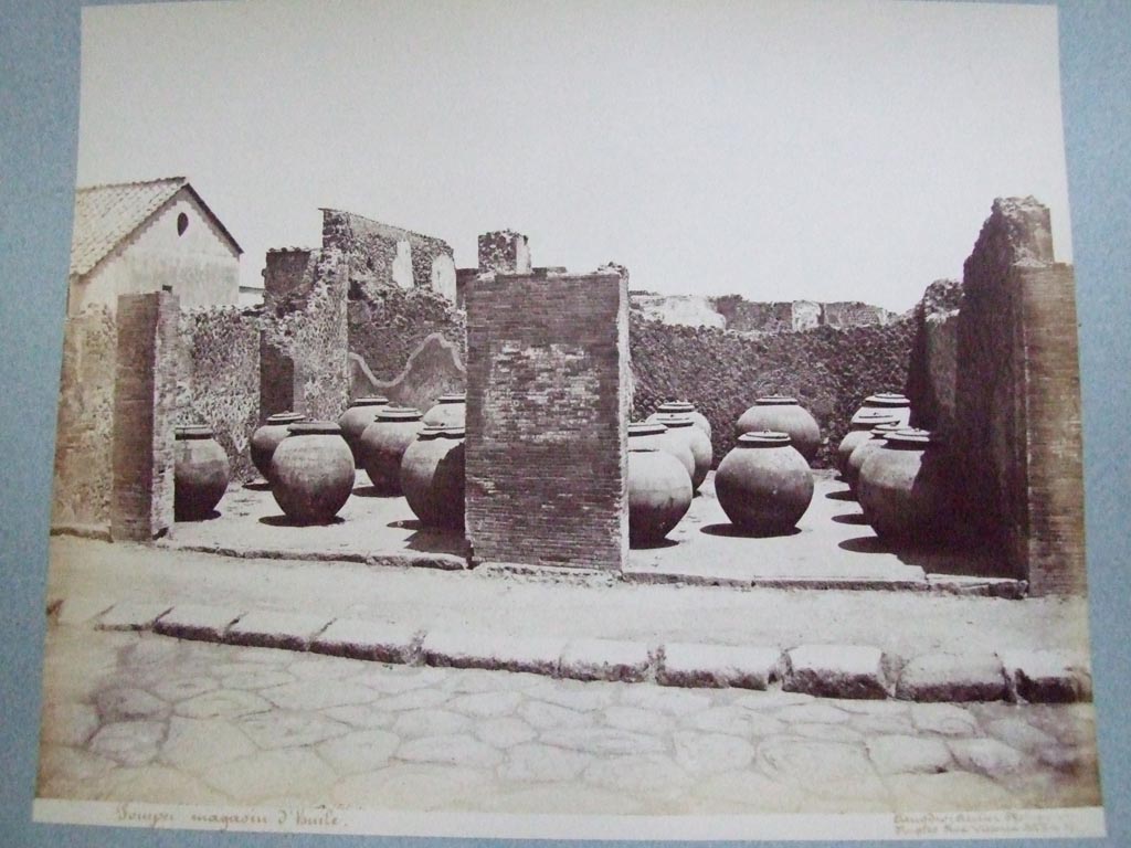 VII.4.13 Pompeii and VII.4.14. Via Foro oil shop. 19th century photograph by Amodio.
Photo courtesy of the Society of Antiquaries, Fox Collection. 
Fiorelli says the two adjacent large shops had these dolia temporarily deposited in them.  
They had come from outside Pompeii near “il Sarno”.  
Some of these are now to be found outside the city wall below the Temple of Venus and the Sarno Baths.
See Pappalardo, U., 2001. La Descrizione di Pompei per Giuseppe Fiorelli (1875). Napoli: Massa Editore. (p.89).
