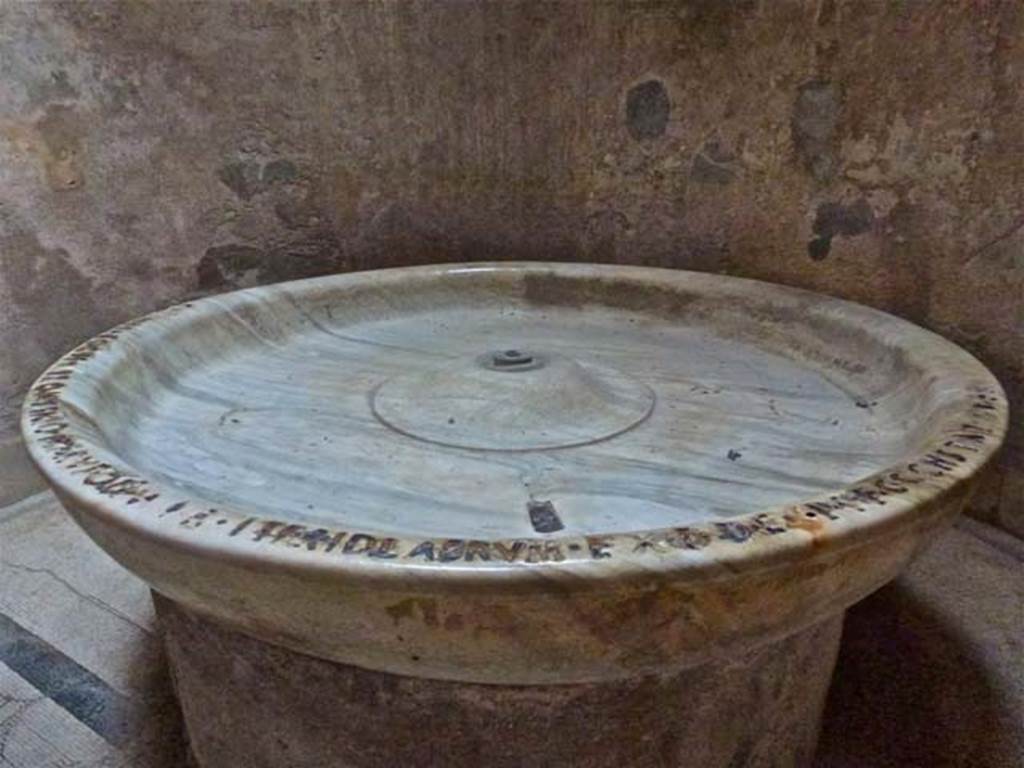 VII.5.24 Pompeii. June 2012. Large marble basin (41) in Caldarium. Photo courtesy of Michael Binns.  
In AD3-4, the duumvirs had a large marble basin set up in the hot room (caldarium). 
Written around the rim in bronze letters is an inscription 
Cn(aeo) Melissaeo Cn(aei) f(ilio) Apro M(arco) Staio M(arci) f(ilio) Rufo IIvir(is) iter(um) i(ure) d(icundo) labrum ex d(ecreto) d(ecurionum) ex p(ecunia) p(ublica) f(aciendum) c(uraverunt) constat HS V(milia)CCL      [CIL X 817]
Cooley translates this as:
“When Gnaeus Melissaeus Aper, son of Gnaeus, and Marcus Staius Rufus, son of Marcus, were duumvirs with judicial power for the second time, they saw to the making of the basin, by decree of the town councillors, at public expense.  It cost 5,250 sesterces.”  [CIL X 817 = ILS 5726]
See Cooley, A. and M.G.L., 2004. Pompeii : A Sourcebook. London : Routledge. (p.81)  
According to Berry, this recorded that it had been added in AD 3-4 by the duumvirs Gaius Melissaeus Aper and Marcus Statius Rufus.
“Gnaeus Melissaeus Aper, son of Gnaeus, and Marcus Statius Rufus, son of Marcus, duumvirs for lawsuits for the second time, had this labrum made at public expense by decree of the town councillors. It cost 5,250 sesterces”.  [CIL X 817]
See Berry, J., 2007. The Complete Pompeii. London: Thames & Hudson.  (p.152)
