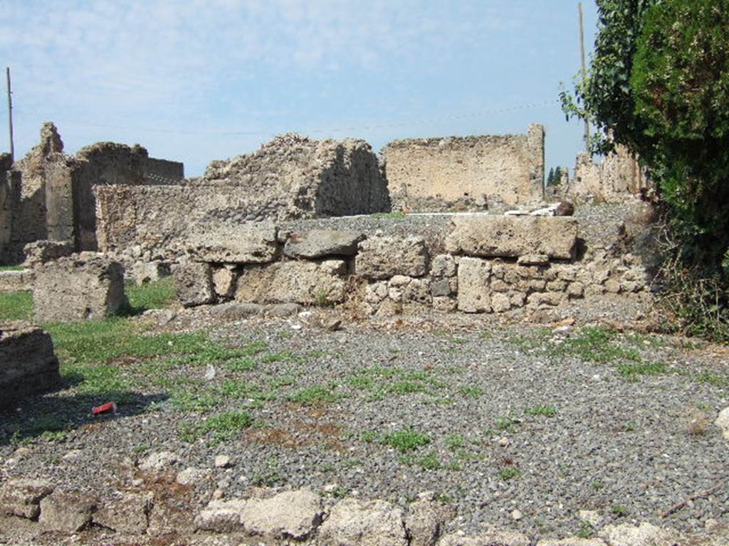 VII.6.26 Pompeii, with VII.6.28 in background. Pompeii. September 2005.
Looking north towards site of shop, which had a counter with two urns and a hearth, a rear room and another smaller rear with a latrine. On the left, the west wall (now vanished) had a doorway linking to the shop at VII.6.27.
