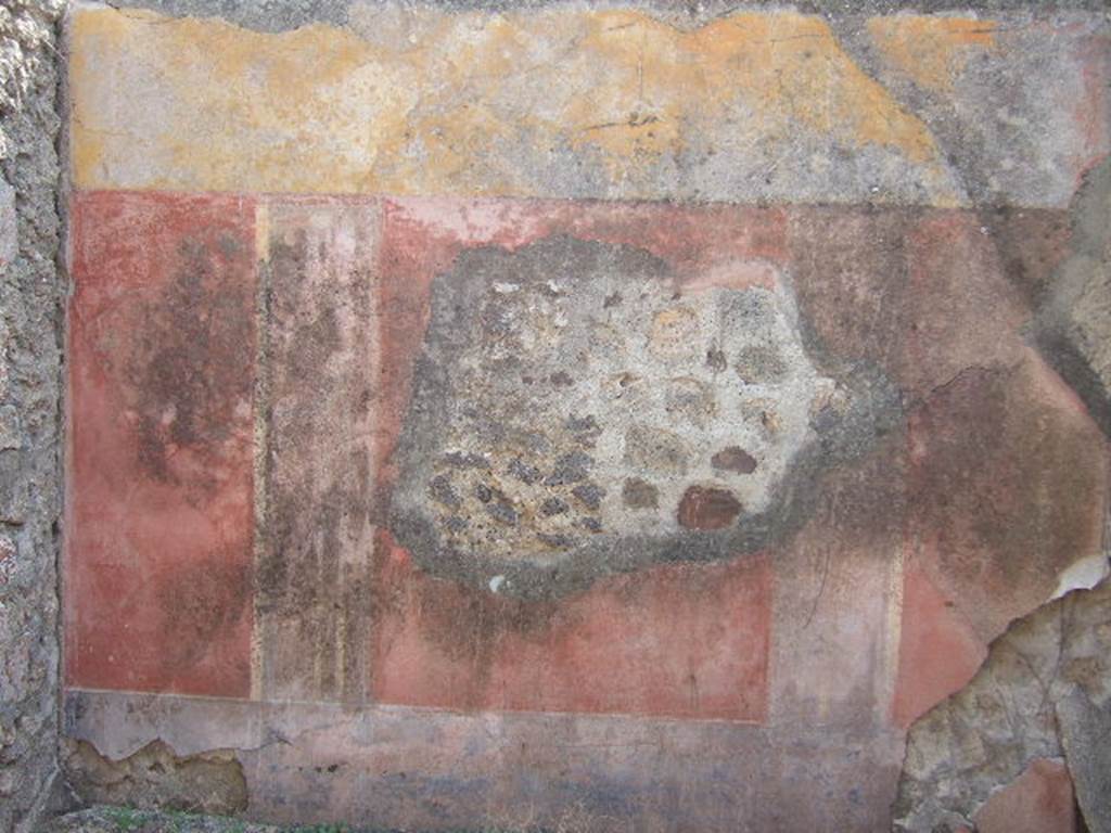 VII.6.30 Pompeii. September 2005. Remains of painted decoration on south wall of room on south side of garden area. According to Spano in NdS, this small room was numbered “143”.
Each wall was painted with three large red rectangles, divided by large areas of black, showing architectural motifs. At the top was a yellow frieze, and the lower zoccolo was painted black. The floor was made from simple coccio pesto. See Spano in Notizie degli Scavi, 1910, (p.483)
