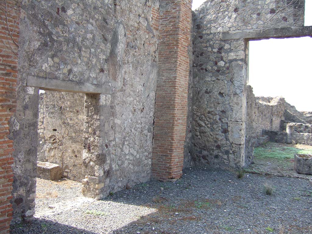 VII.7.23 Pompeii. September 2005. 
South wall of atrium with doorway to area of kitchen, cubiculum, rustic rooms and steps to upper floor.
