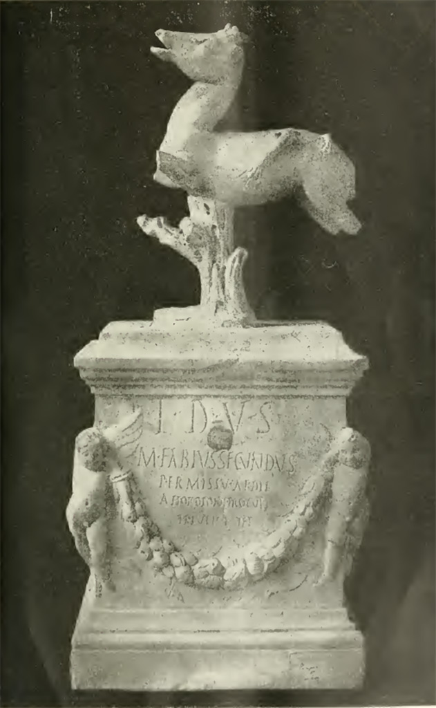 VII.7.32 Pompeii. Inscribed statue and base found 25th March 1817.
Now in Naples Archaeological Museum. Inventory number 3762.

Secondo Tarallo, trattasi di una basetta di marmo alta mm. 380, lunga mm. 340 e larga mm. 235. Nella parte anteriore, ai due angoli, sono rilevati due graziosi puttini o amorini che sostengono un festone di fiori e frutti. Tra la cornice superiore della basetta, ed il festone v'è incisa la seguente iscrizione:
T D V S
M FABIVS SECVNDVS
PERMISSV AEDIL
A HORDIONI PROCVLI
TI IVLI RVFI
Nella parte posteriore, ai due angoli, sono scolpiti a rilievo due uccelli, sulle due facce laterali pendono due altri festoni di foglie. Sormonta la basetta un quadrupede con le gambe stroncate, il quale è sorretto da un tronco d'albero. Sul dorso di esso si osservano i vesti di quattro zampe di un altro animale che gli è saltato addosso per dilaniarlo. Il tutto, compresa la base, è alto mm. 710. 

Parecchi studiosi presero ad esaminare il donarlo: ognuno manifestò la propria opinione; ma, poiché non si fu sempre di accordo nel determinare la divinità, a cui appartenesse il tempio, ove era stato rinvenuto, ne segni che non si fu sempre d'accordo nel determinare il nume, a cui quello fosse consacrato. Questa varietà d'opinioni proveniva dal fatto, che proprio il nome del nume era celato sotto le sigle T-D-V-S.

According to Tarallo, this is a marble base 380mm high, 340mm long and 235mm wide. In the front, at the two corners, there are two graceful cherubs or cupids holding up a festoon of flowers and fruit. 
Between the upper frame of the base and the festoon there is the following inscription: 
T D V S 
M FABIVS SECVNDVS 
PERMISSV AEDIL
A HORDIONI PROCVLI 
TI IVLI RVFI 
On the back, at the two corners, two birds are sculpted in relief, on the two side faces hang two other festoons of leaves. 
The base is surmounted by a quadruped with its legs missing, which is supported by a tree trunk.
On its back are the vestiges of four legs of another animal that jumped on it to tear it to pieces. 
The whole, including the base, is 710 mm high. 

Several scholars began to examine the donation: each expressed his opinion, but, since they were not always in agreement in determining the deity, to whom the temple belonged, where it was found, they were not always in agreement in determining the deity, to whom it was consecrated. This variety of opinions stemmed from the fact that the very name of the deity was hidden under the initials T-D-V-S.

Vedi/See Tarallo, E. Intorno al Donario del Pompeiano Marco Fabio Secondo in Rendiconti (Lincei) della Classe di scienze morali, storiche e filologiche, s5, v21, 1912, p. 69-78 and Tav. p. 78.

