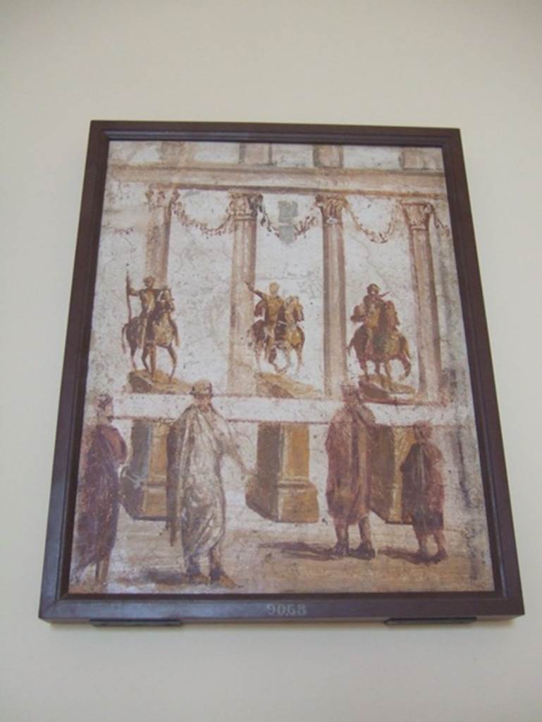 Part of the “Forum Frieze” found in the atrium of II.4.3.  
Forum scene of people reading a banner across the front of the equestrian statues.  Now in Naples Archaeological Museum.  Inventory number 9068.


