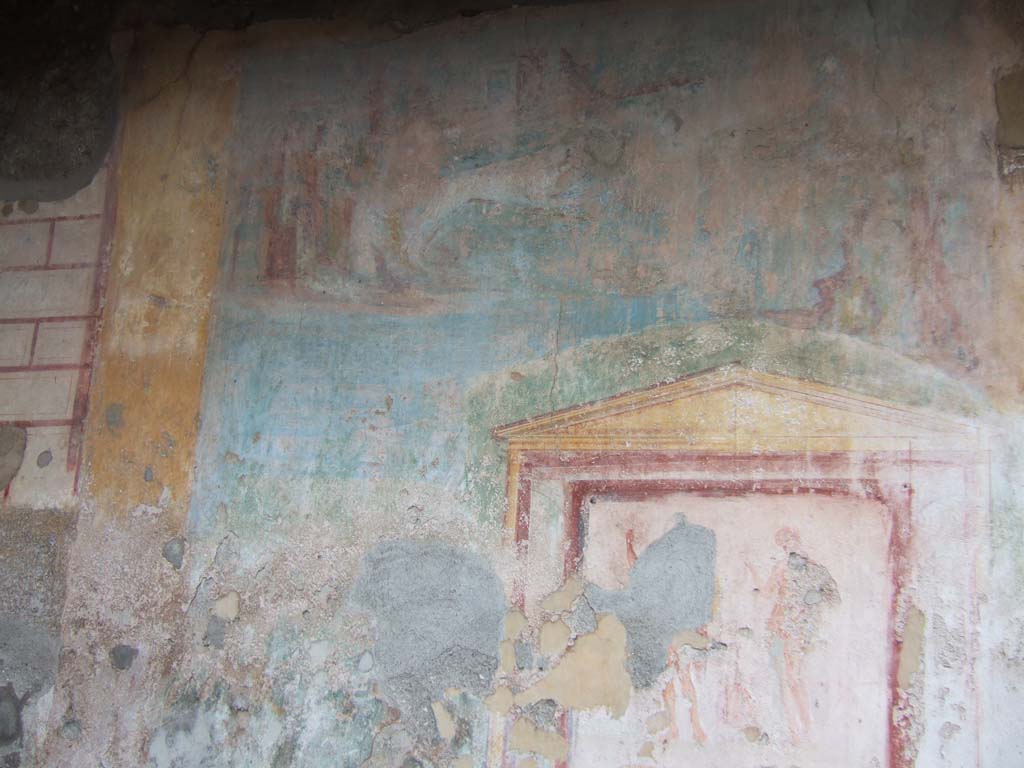 VII.9.33 Pompeii. December 2005. Remains of large landscape painting on west wall, with the lararium painting below.
According to Jashemski, this site, excavated in 1822-23, was badly damaged by the earthquake or at an earlier period.
It had 3 rooms on the right (north).
On the left a door to the adjacent shop, and behind this, a dormitory, a latrine, a stairway leading to the upper floor, and a kitchen.  
Fiorelli believed the site was used as a caupona.  
The area between the rooms on the right and on the left is difficult to explain.  
The rear wall opposite the wide entrance was decorated with a landscape with a lararium painting in the lower right.
The shrine was framed by a twining vine shoot on which various birds were perched.  
The excavators expected the structure underneath the aedicula to be an altar, but it was found to be a fountain filled with lapilli and other volcanic debris.  
The mosaic pavement around the fountain pictured a variety of dolphins and geese.  
The mosaic, however, had been damaged by later construction. 
It would appear that the area in which the fountain stood was once a garden. It may have lasted, in part, as a garden – in part, as a courtyard.
She pointed out that Boyce called the area of the Lararium “a kitchen”.
See Jashemski, W. F., 1993. The Gardens of Pompeii, Volume II: Appendices. New York: Caratzas. (p.189).
