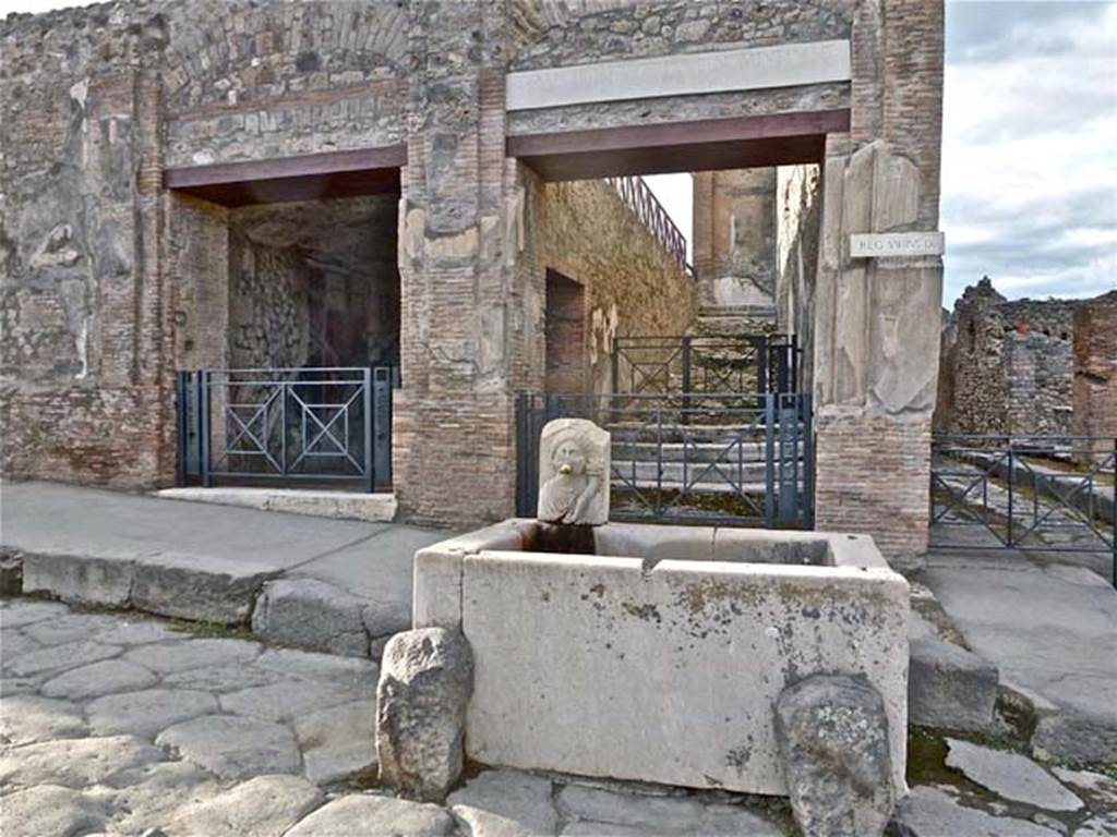VII.9.68/67 Pompeii. September 2011. Looking north to entrance doorway on left side of fountain.  Photo courtesy of Michael Binns. According to Cooke Cockburn and Donaldson, there is a flight of stairs leading into the street by a doorway. At the bottom of the stairs is a small chamber, having an opening into the street, and one on the landing at the foot of the staircase. The walls of this chamber are embellished with various paintings on a black background, among which is a remarkable landscape, having in the distance lofty mountains, a river winding through verdant meadows, with herds and shepherds and views of villas, and in the foreground a statue, before which is a group offering sacrifices. There is a fountain in the street, immediately opposite the door of the staircase. The outer elevation of the walls towards the two streets is decorated in stucco with pilasters, cornices and pediments, lightly relieved, and not inelegant in detai, (see VII.9.67).
See Cooke Cockburn Donaldson, Pompeii, pt. 1, 1827, (p.53)


