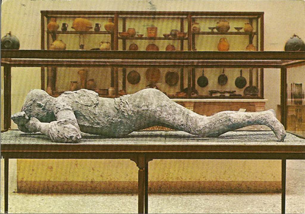 VIII.1.4 Pompeii Antiquarium. Cast of female victim with cabinet of terracotta jars and kitchen utensils at the back. Photo courtesy of Rick Bauer.