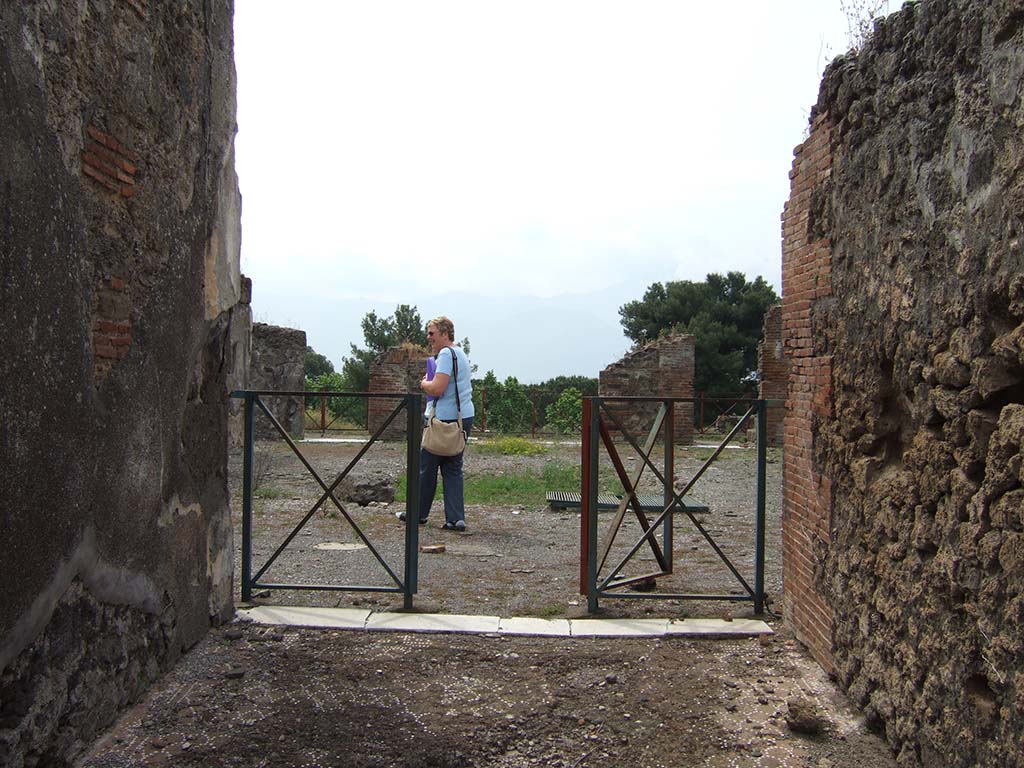 VIII.2.34 Pompeii. May 2006. Looking south from entrance fauces or corridor, towards atrium.
According to Mau, the floor of the entrance corridor was separated from the atrium flooring by a threshold of white marble with some dark veining; 
at its ends you could see the holes for the door hinges. 
There were no bolts; so, to fasten the door closed there were no other means than to unite the two shutters, either with a lock or some other way.
See Mau, Bullettino dell’Instituto di Corrispondenza Archeologica (DAIR), 1886, (p.149).
