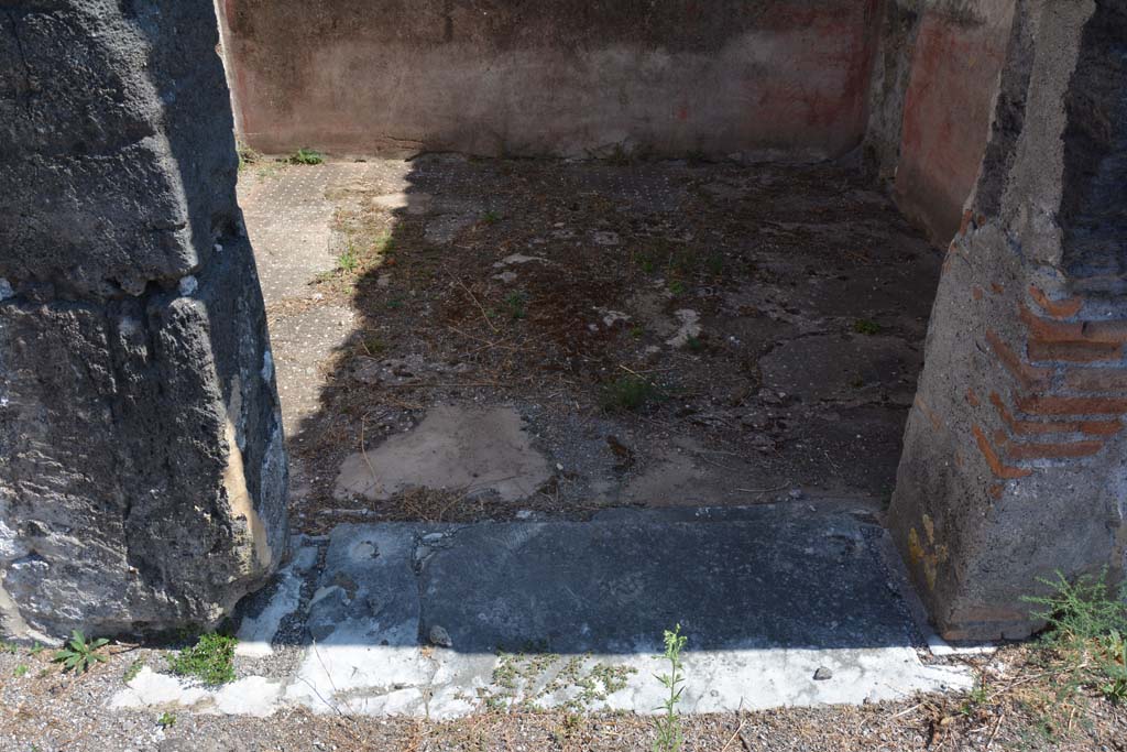VIII.2.34 Pompeii. May 2006. Doorway to cubiculum ‘g’, on east side of atrium, next to east ala. The threshold was of travertine with housing for the hinges of the door with two shutters opening towards the Interior of the room, like those of all the other rooms around the atrium. The walls were decorated with a red zoccolo partitioned into simple geometric panels. In the middle of the walls, the red central panel was separated from the yellow side panels by a narrow white panel. The upper zone of the walls were completely faded, but conserved a trace of a stucco cornice. On the east wall, visible through the doorway, the large hole made by previous excavators or perhaps by burrowers after the eruption, can be seen.
