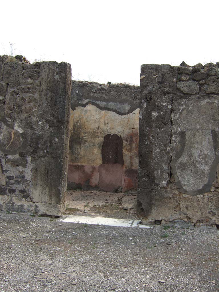 VIII.2.34 Pompeii. May 2006. Doorway to cubiculum ‘g’, on east side of atrium, next to east ala.
The threshold was of travertine with housing for the hinges of the door with two shutters opening towards the Interior of the room, like those of all the other rooms around the atrium. 
The walls were decorated with a red zoccolo partitioned into simple geometric panels.
In the middle of the walls, the red central panel was separated from the yellow side panels by a narrow white panel.
The upper zones of the walls were completely faded, but conserved a trace of a stucco cornice.
On the east wall, visible through the doorway, the large hole made by previous excavators or perhaps by burrowers after the eruption, can be seen.
