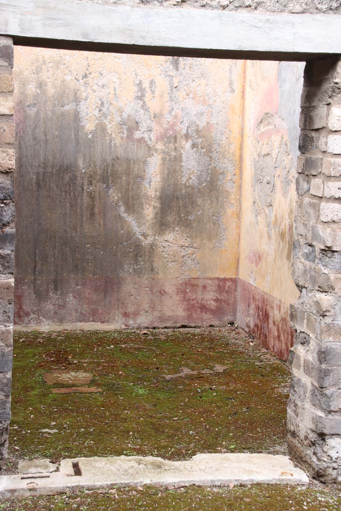 VIII.3.12 Pompeii. October 2020. Looking west towards doorway to oecus.
The west wall of the oecus can be seen, which still shows some of the red panelled zoccolo painted with plants. 
The middle of the wall was decorated with a yellow background, but the decoration has completely faded and disappeared. 
The upper zone was painted white with a simple stucco cornice.
