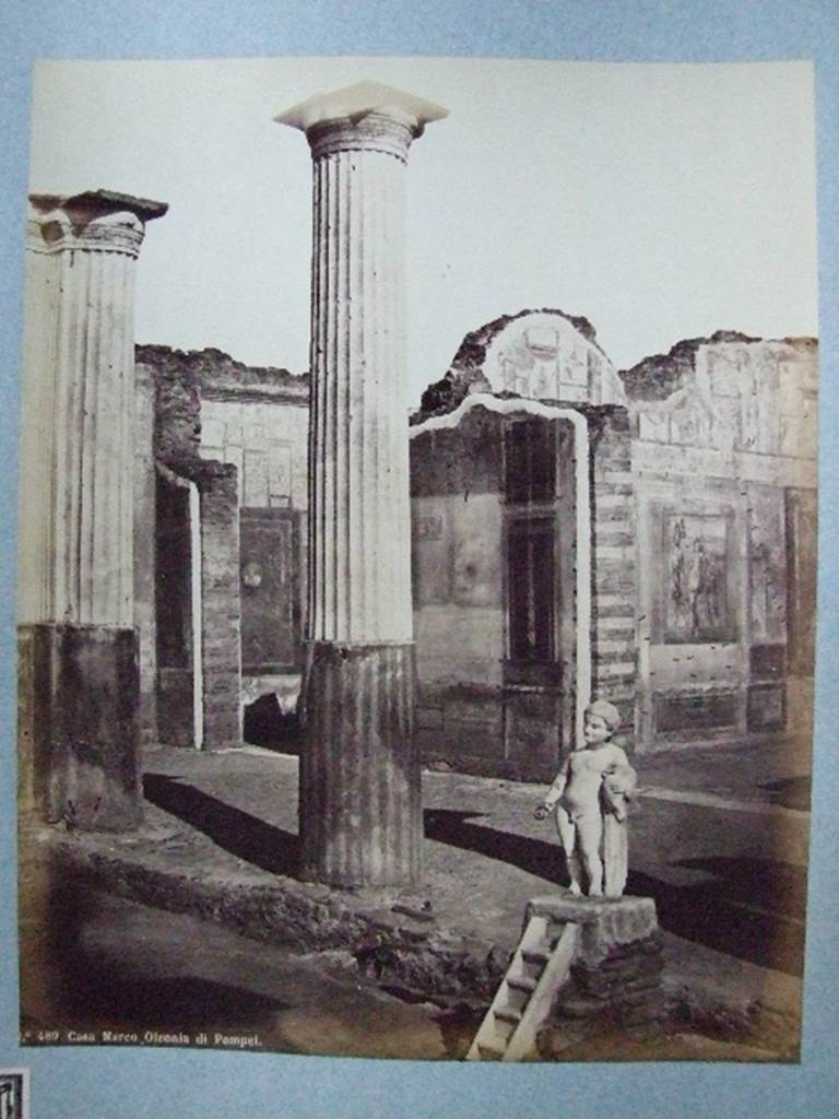 VIII.4.4 Pompeii. Fountain and south portico of peristyle. Old undated photograph.
Courtesy of Society of Antiquaries, Fox Collection.
According to Dyer:
Two of the rooms on the further side of the peristyle, and at the extremity of the house, are visible in this view.
The smaller one, on the left, appears to be a bedchamber.
The floor is of opus Signinum; the walls painted mostly red and yellow, apart from the usual architectural ornaments, also have pictures of Nereids riding through the waves on sea-monsters.
The picture facing the entrance, so far as can be made out, represented the Dioscuri.
Next to this room, on the right, is a large and handsome exedra, or retiring room.
It is paved with black and white marble, and has in its middle a small impluvium or basin; from which we may infer that there was a corresponding aperture in the roof.
The walls were adorned with small but well-executed pictures.
On the facing wall was Narcissus admiring himself in the fountain.
On the left wall a Hermaphrodite leaning on the shoulder of Silenus could be seen.
On the right wall, Bacchus accompanied by his usual troop, discovering Ariadne. 
See Dyer, Thomas, 1867: The Ruins of Pompeii. London: Bell and Daldy, (p.80).


