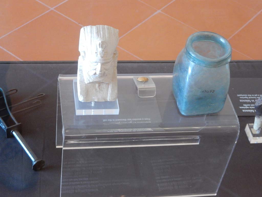 VIII.7.28 Pompeii. June 2019. Egyptian style small herm, from the temple enclosure.
Glass jug, from the temple courtyard, the lower part being decorated with a Victory with crown and palm.
Now in Naples Archaeological Museum. Photo courtesy of Buzz Ferebee. 
