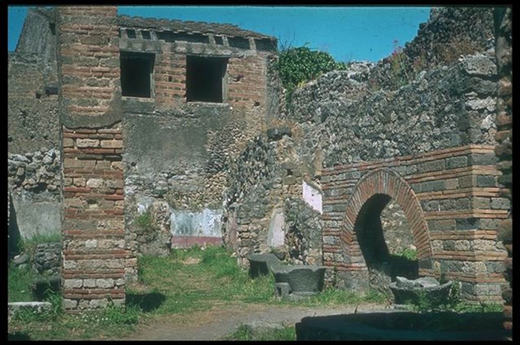 IX.3.12 Pompeii. Looking north-east from entrance. Photographed 1970-79 by Günther Einhorn, picture courtesy of his son Ralf Einhorn. According to Boyce and Frohlich, the large rectangular pilaster opposite the oven used to be decorated with white stucco to a height of about two metres. See Boyce G. K., 1937. Corpus of the Lararia of Pompeii. Rome: MAAR 14. (p. 83 and pl. 20). See Fröhlich, T., 1991. Lararien und Fassadenbilder in den Vesuvstädten. Mainz: von Zabern. (p. 295 and Taf. 45.2)