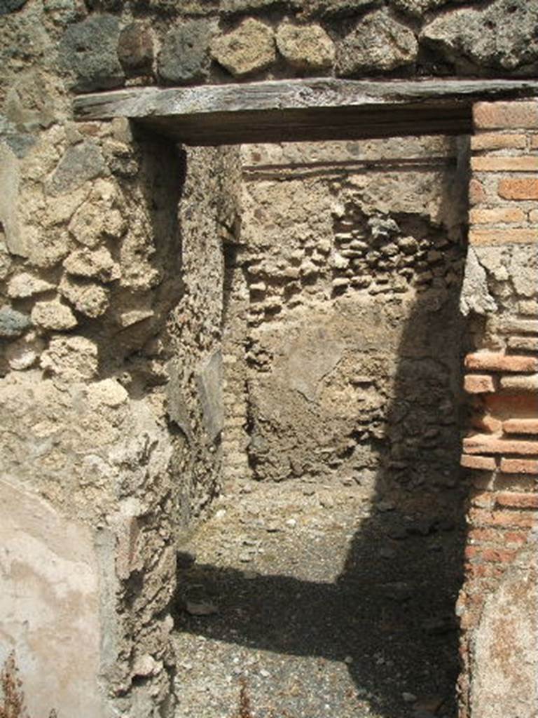 IX.6.a linked to IX.6.1 Pompeii. May 2005. Doorway to rear on north-west side of shop, with doorway to IX.6.1. Left of centre, on the west wall, the line of the site of the stairs can be seen in the plaster remains. According to Flohr, this room contained the stairs to the upper floor, which extended above all three ground-floor rooms. See Rivista di Studi, XVIII, 2007, article by Flohr, M, entitled Cleaning the laundries report of the 2006 season, (p.134).

