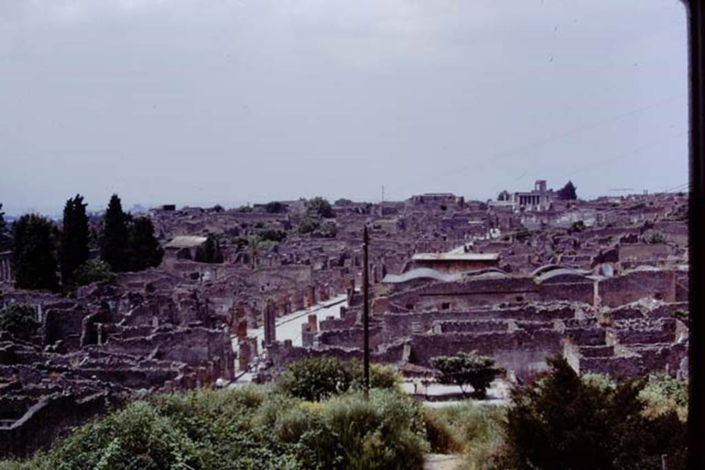 View looking west along the Via dell’Abbondanza, taken from above IX.7.12, Pompeii, 1973. Photo by Stanley A. Jashemski. 
Source: The Wilhelmina and Stanley A. Jashemski archive in the University of Maryland Library, Special Collections (See collection page) and made available under the Creative Commons Attribution-Non Commercial License v.4. See Licence and use details. J73f0233
