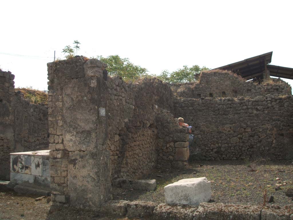 IX.7.23 Pompeii. May 2005. Looking south across caupona to narrow rear room. According to Mau, immediately behind the threshold of the main room, lay a large stone square block of travertine (0.90 long, 0.58 wide and 0.46 high). He thought this probably served as the base for a wooden table, around which the customers would settle down to eat. He also said the threshold of this main room seemed to have been made of wood. See Mau in BdI, 1882, (p.183)
According to Eschebach, the podium used to be on the west side (right of photo) of the caupona, the rear room had the hearth and a window looking into the caupona. See Eschebach, L., 1993. Gebudeverzeichnis und Stadtplan der antiken Stadt Pompeji. Kln: Bhlau. (p.435)

According to Della Corte, this caupona was attributed to Ti. Claudio Epafrodito, because of the seal/signet brought to light here 
Ti. C(laudius) Ep(aphroditus)    [CIL X 8058,9]. 
He was well noted as producer of wine, one of his numerous named amphora was found in an adjacent atrium.  See Della Corte, M., 1965.  Case ed Abitanti di Pompei. Napoli: Fausto Fiorentino. (S.27 on p.197)
