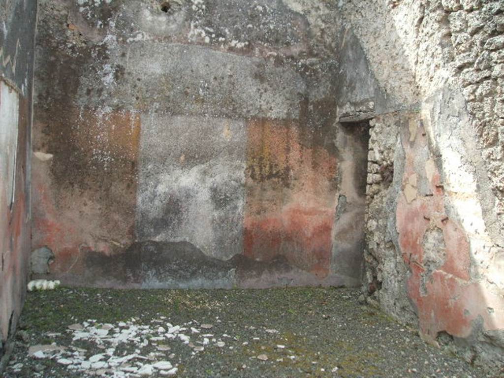 IX.7.25 Pompeii. May 2005. Looking south in tablinum “o”, with doorway in west wall to a small room or cupboard, room “n”. According to Mau, when this house was being used as a hospitium, both the tablinum and ala were probably used as triclinia. However, he conceded that in this tablinum, the couches would have made access to the small room on the right very difficult. The rear wall of the tablinum was painted with a white background in the middle, with red on either side. A painted flying cupid could be seen on the white background, with a thyrsus in his left-hand, a cantharus in his right, and a red cloak on his back. See Mau in BdI, 1882, (p.177 & 179)
