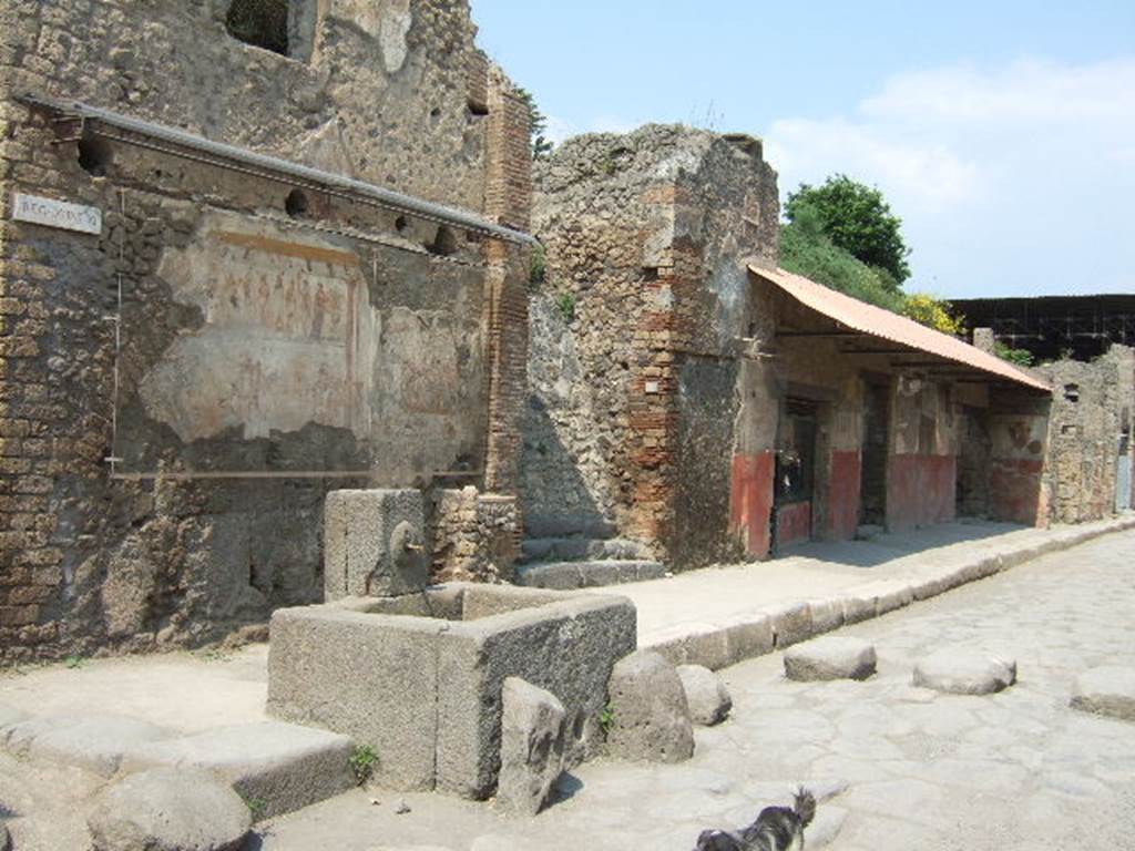 IX.11.1 Pompeii. May 2006. Looking north-east along Via dell’Abbondanza towards house with street shrine and fountain, left. and Thermopolium of Asselina, right. According to Della Corte, written on the street shrine above the altar with the last sacrifice in honour of the 12 gods, were the names of the Vicomagistri, reading  –
Successus, Victor
Asclepiades, Co(n)sta(n)s      (Vicomagistri)        [CIL IV 7855]
See Della Corte, M., 1965.  Case ed Abitanti di Pompei. Napoli: Fausto Fiorentino. (p.307)

