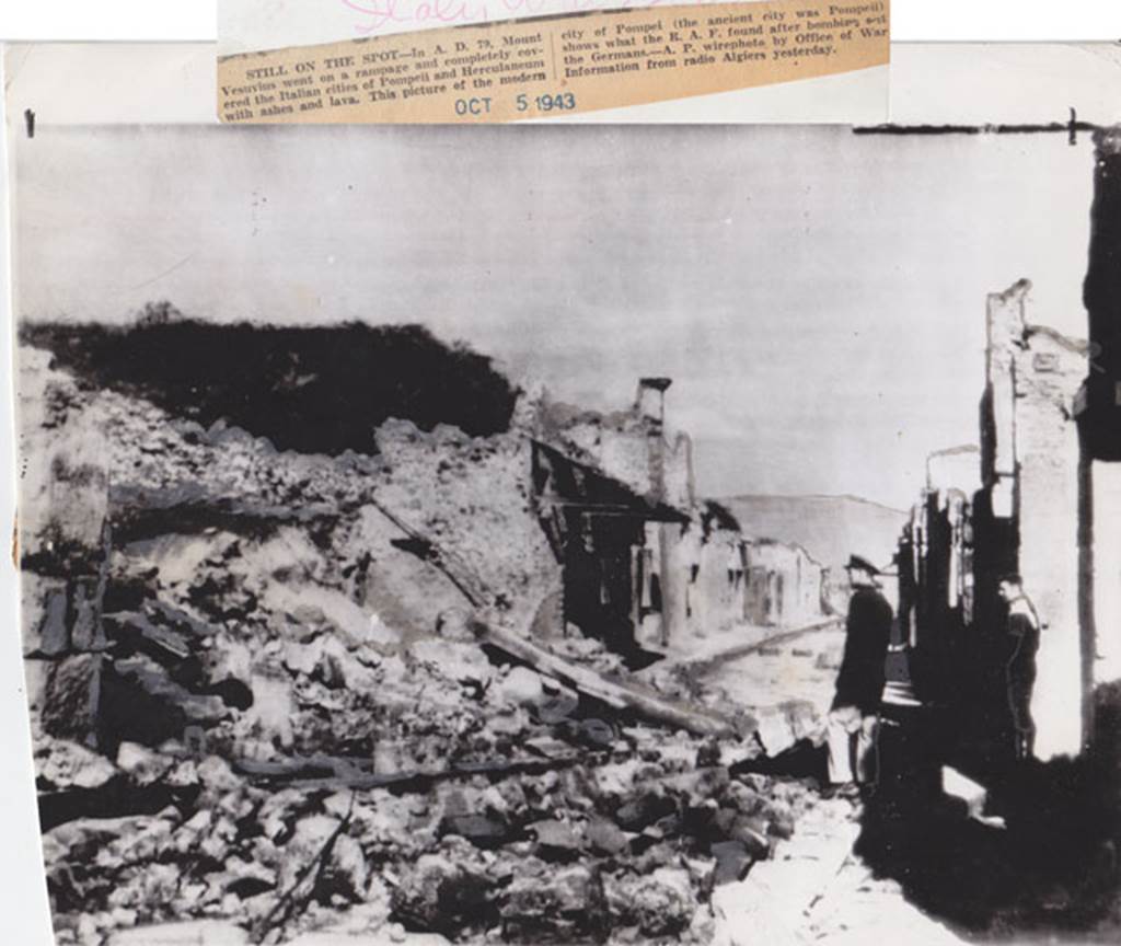 IX.12.1 Pompeii. October 1943. Looking east between IX.12 and I.8 on Via dell’Abbondanza. Picture that according to the newspaper report “shows what the RAF found after bombing.....”.  The destroyed Houses of the Cenacoli Colonnati, following the aerial bombardment of 1943.  Photo courtesy of Drew Baker.
The left pilaster of the front façade of IX.12.1 can be seen on the left.

