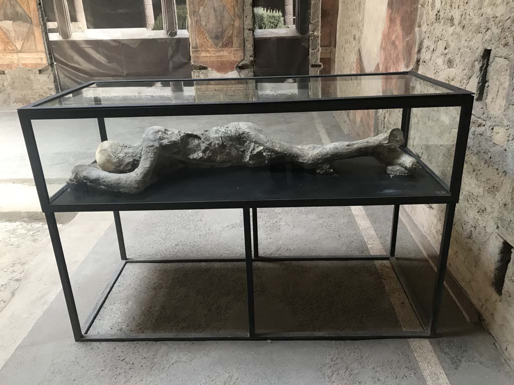 Villa of Mysteries, Pompeii. April 2019. Room 64, looking east across atrium towards display case on south-east side.
This contains the plaster-cast of a body of a man found in Room 35, on the other side of the peristyle.
Photo courtesy of Rick Bauer.
