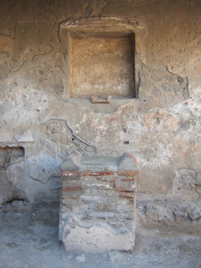 Villa of Mysteries, Pompeii. May 2006. Room 61, niche in north wall, with remains of stucco pediment above. According to Boyce, the small altar embedded in the floor of the niche, was decorated with an image of a gorgon and two heads of bulls. Two sculptured heads, a terracotta one of a goddess and another of tufa representing Hercules, were found inside the niche. See Boyce G. K., 1937. Corpus of the Lararia of Pompeii. Rome: MAAR 14. (p.97) 