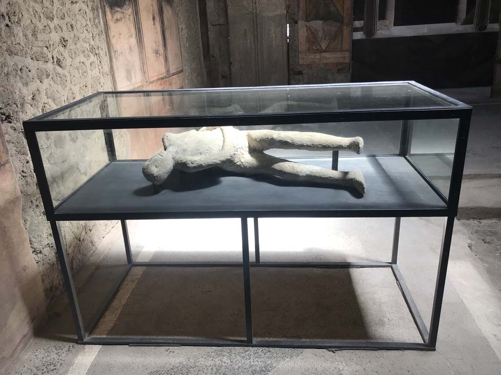 Villa of Mysteries, Pompeii. April 2019. Room 64, looking east across atrium towards display case on south-east side.
This contains the plaster-cast of a body of a man found in Room 35, on the other side of the peristyle.
Photo courtesy of Rick Bauer.
