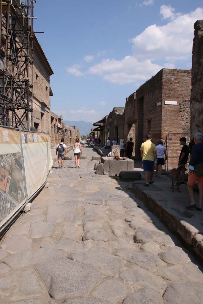 Via dell’Abbondanza, Pompeii. September 2021. 
Looking east to fountain in roadway between IX.13 and I.9. Photo courtesy of Klaus Heese.
