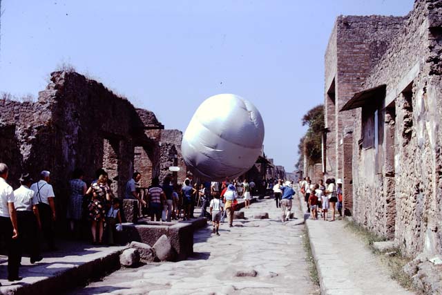 Via dell’Abbondanza, Pompeii. 1974. Looking west towards I.13 (behind balloon) and III.3. Photo by Stanley A. Jashemski.   
Source: The Wilhelmina and Stanley A. Jashemski archive in the University of Maryland Library, Special Collections (See collection page) and made available under the Creative Commons Attribution-Non Commercial License v.4. See Licence and use details. J74f0395

