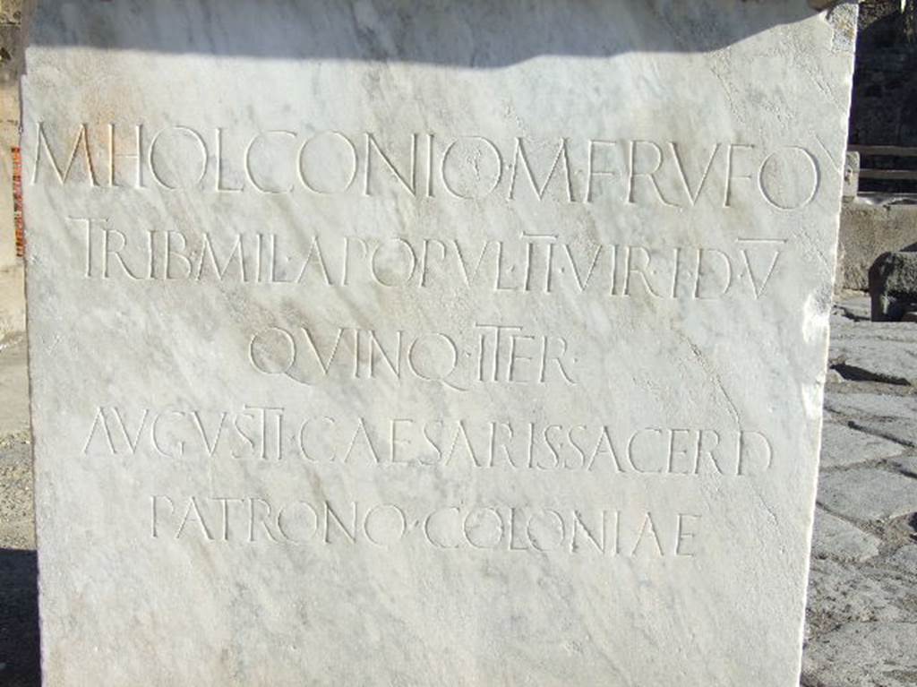Via dell’Abbondanza, outside VII.1.12 Pompeii. May 2010. 
Inscription on base of a statue of M. Holconius Rufus.
M. HOLCONIO.  M. F. RVFO 
TRIB. MIL. APOPVL. II VIR. I. D. V.
QVINQ. ITER.
AVGVSTI. CAESARIS. SACERD.
PATRONO. COLONIAE. 

