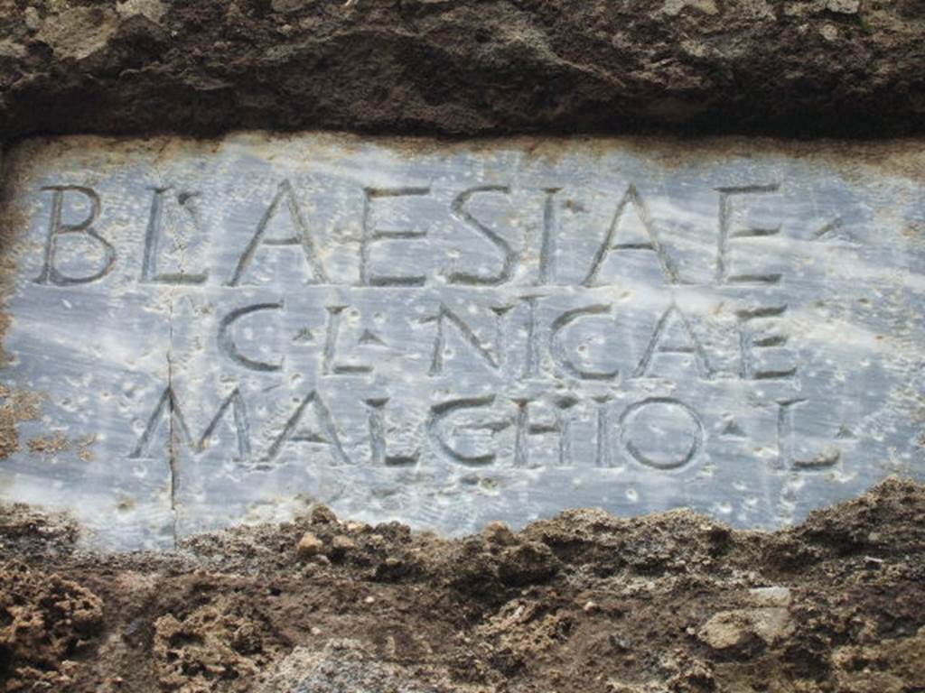 FPNH Pompeii. December 2005. Light blue marble plaque in centre of south side, with inscription.
According to D’Ambrosio and De Caro, this read

BLAESIAE C. L. NICAE MALCHIO L.

They expand this to

Blaesiae
C(ai) l(ibertae, Nicae 
Malchio l(ibertus)

See D’Ambrosio A. and De Caro S., 1988. Römische Gräberstraßen. München: C.H.Beck. p. 212.
