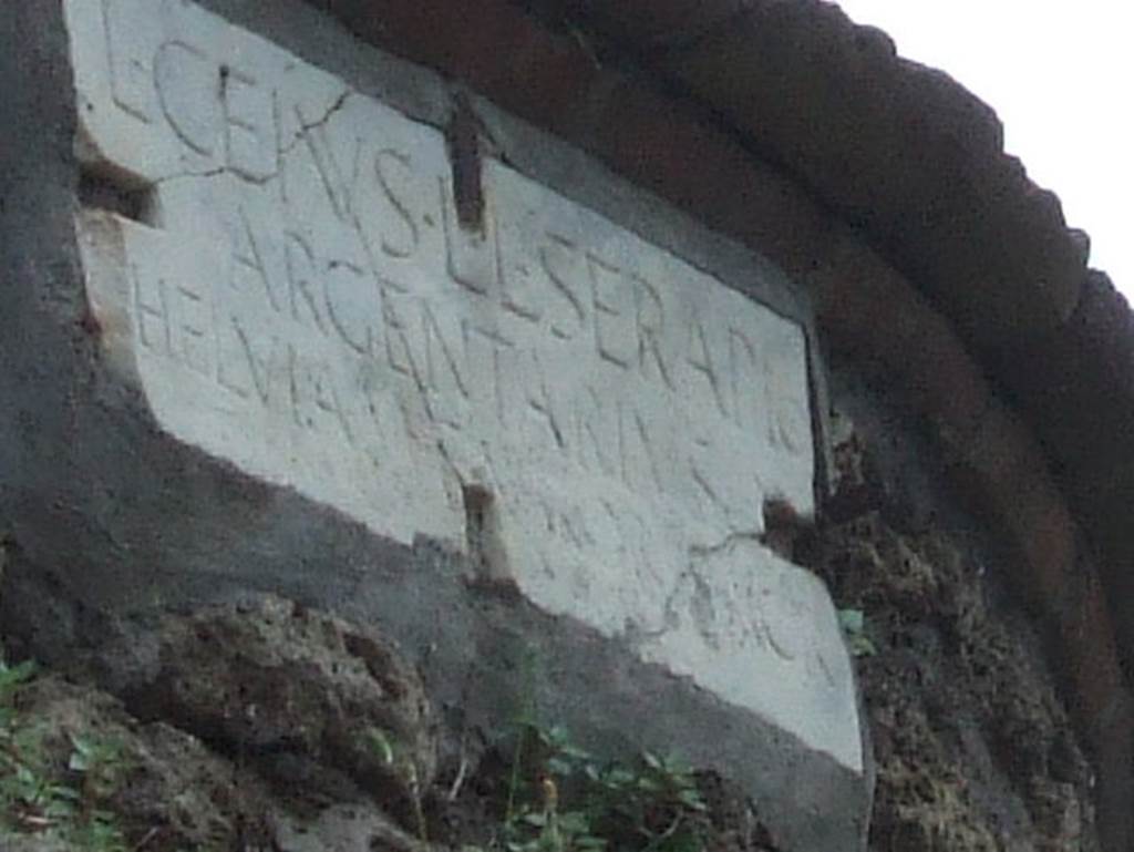 Pompeii Porta Nocera Tomb 3OS. Marble plaque with latin inscription:
L(ucius)  CEIVS  L(ucii)  L(ibertus)  SERAPIO
ARGENTARIVS
HELVIA  M(arci)  F(ilia)  VXOR  SACR(averunt).

