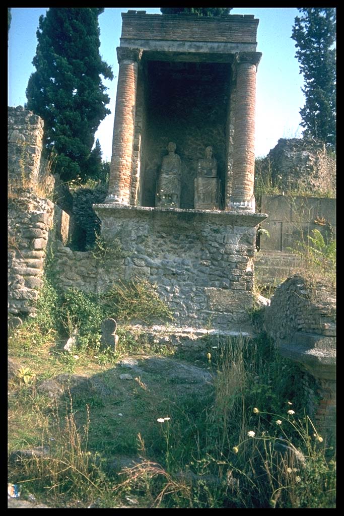 Pompeii Porta Nocera. Tomb 9OS. Tomb of a magistrate? Two columellae at front of tomb.
Photographed 1970-79 by Günther Einhorn, picture courtesy of his son Ralf Einhorn.
According to Stefano De Caro, in the space in front of the façade five columellae were found, three of which appear in situ in the excavation photos [1954] and only one in tuff is preserved in front of the SE corner of the tomb. In front of this, under a stone slab put for protection, a cinerary urn was found. Two other urns were found in correspondence with the next columella towards the west and one finally "between the fourth and fifth columella". Today [1983], not in situ, a lava columella lies in the area.
See D’Ambrosio, A. and De Caro, S., 1983. Un Impegno per Pompei: Fotopiano e documentazione della Necropoli di Porta Nocera. Milano: Touring Club Italiano, 9OS.

