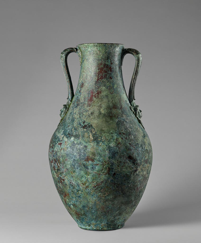 Discovered in a villa in Boscoreale. Bronze amphora with two handles each with a female head wearing a lion’s skin—possibly depicting Omphale.
Digital image courtesy of the Getty's Open Content Program. Now in the Getty Museum, inventory number 72.AC.139.
Two handles provide the only decoration on this tall amphora (storage jar). Attachments at the base of each are fashioned in the shape of a female head wearing a lion’s skin—possibly depicting Omphale, a mythical queen of Lydia (in present-day Turkey), to whom the hero Hercules was enslaved for a time.
Vessels of this type were frequently used to hold wine at banquets. This amphora was discovered in a villa at Boscoreale or in the vicinity, although the exact findspot is unknown. 
