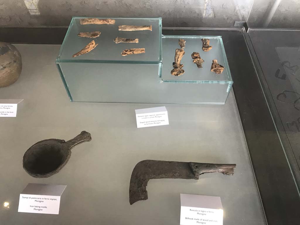 Complesso dei triclini in località Moregine a Pompei. April 2019.
Top: Shaped wooden elements belonging to furniture.
Right: Wood and iron billhook.
Left: Two iron baking moulds.
Photo courtesy of Rick Bauer.
