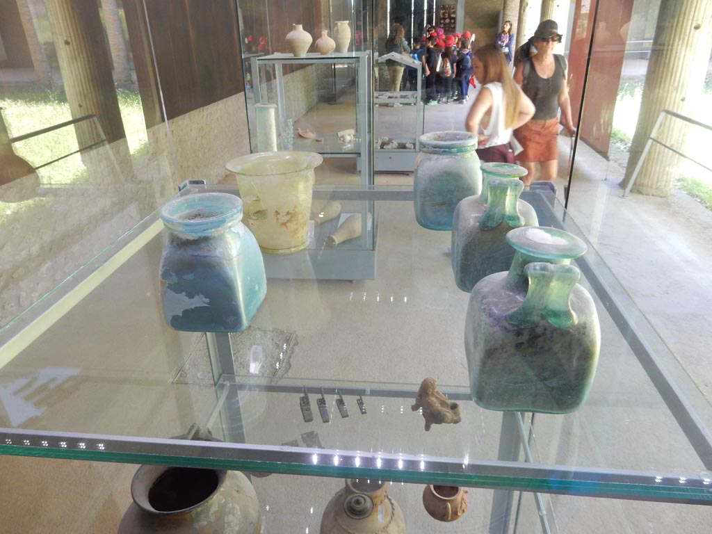 Complesso dei triclini in località Moregine a Pompei. May 2018. Glass tableware on display in Pompeii Palaestra.
Single handed jug in moulded glass.
Single handed jug in moulded glass bearing the makers mark made of concentric circles.
Blown glass beakers.
Single handed drinking cup made of blown glass.
Blown glass perfume vessel.
Photo courtesy of Buzz Ferebee.