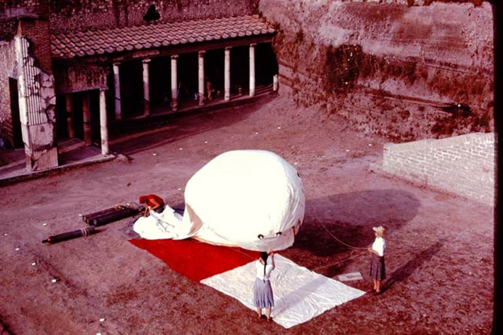 Oplontis, 1977. The balloon being filled, which would be used to photograph from the air. Looking south-west towards the west portico, the rows of root cavity can be seen cleanly painted white. Photo by Stanley A. Jashemski.   
Source: The Wilhelmina and Stanley A. Jashemski archive in the University of Maryland Library, Special Collections (See collection page) and made available under the Creative Commons Attribution-Non Commercial License v.4. See Licence and use details. J77f0262
